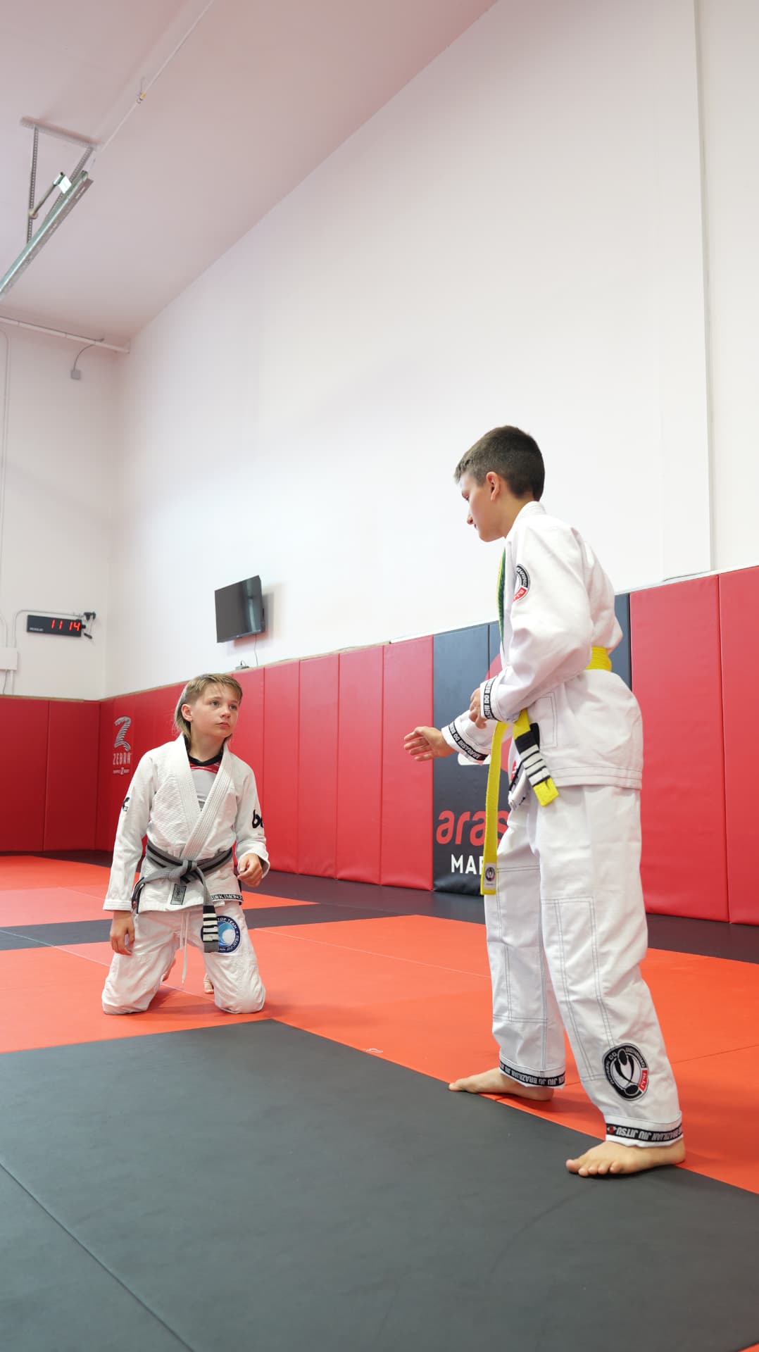 Two kids' BJJ students facing off to start a drill on the mats at Arashi-Do Red Deer