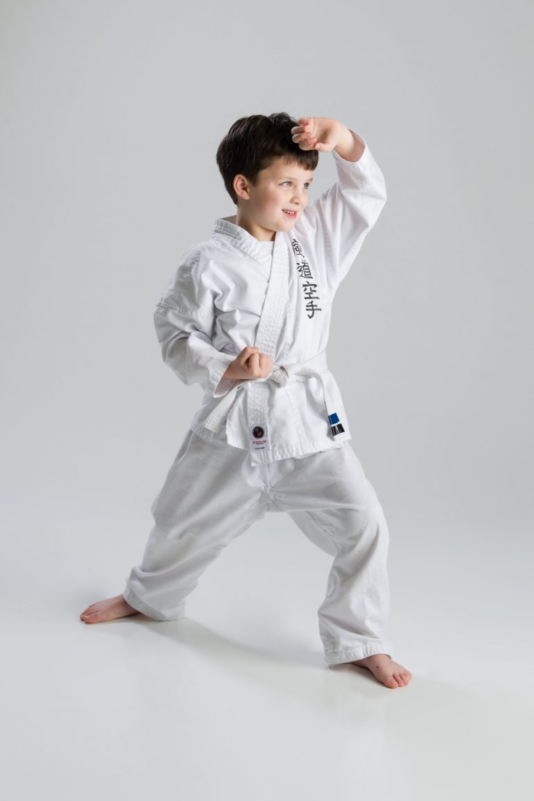 Young white-belt karate student in a blocking stance at Arashi-Do Red Deer