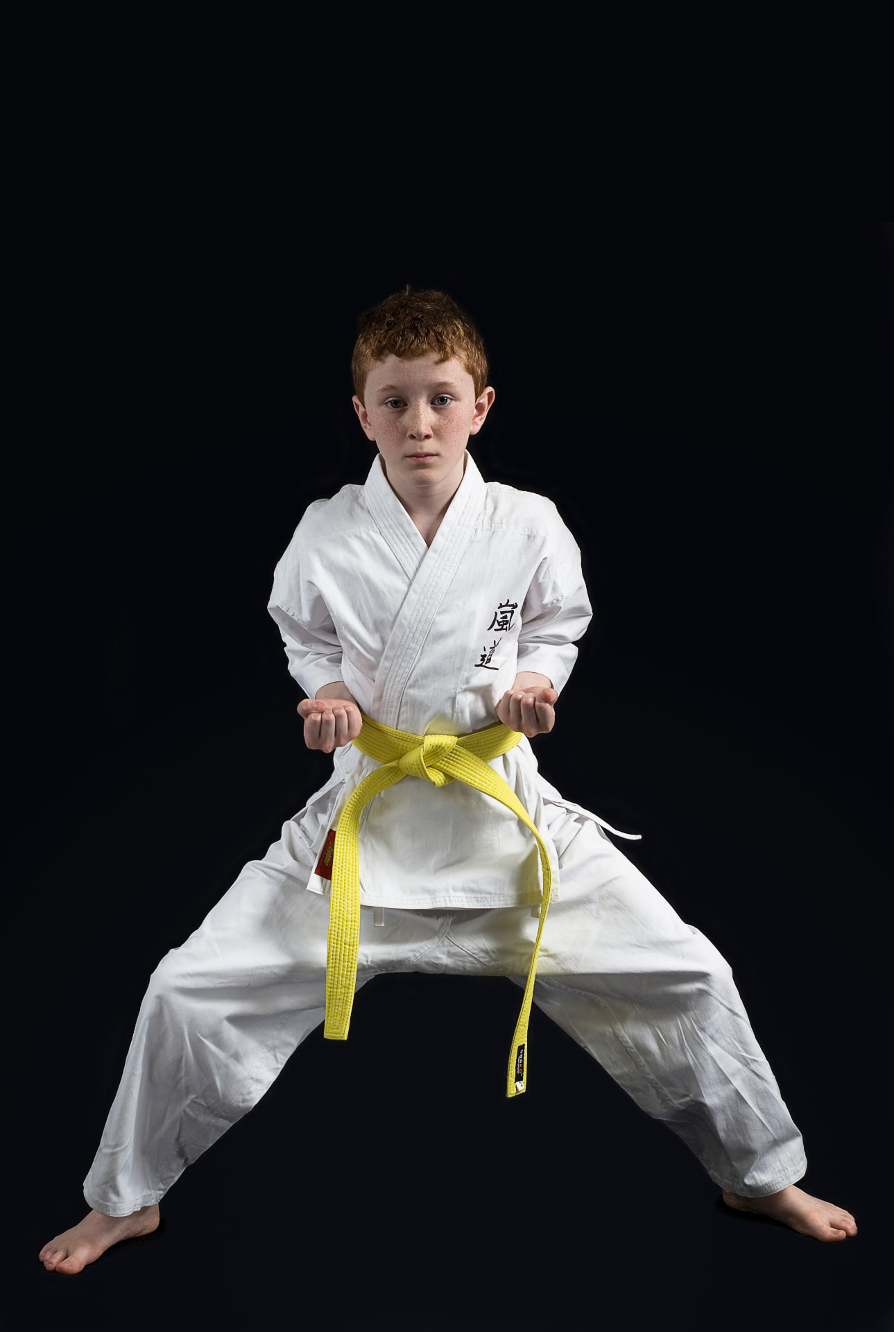Young Arashi-Do Red Deer karate student in a white gi and yellow belt holding a strong stance