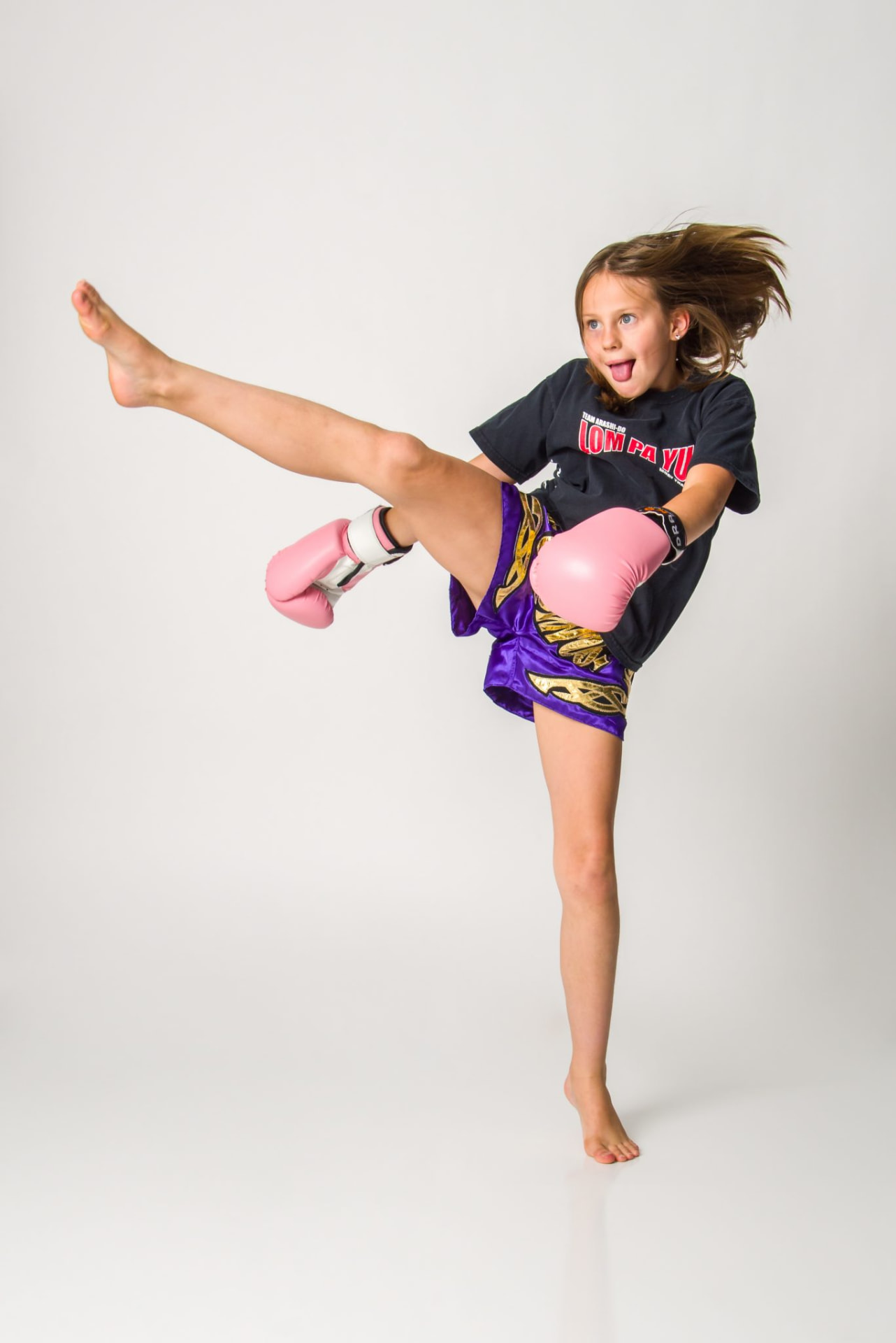 Junior Arashi-Do Muay Thai student throwing a high kick in branded Lom Pa Yu gear